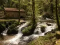 Antigua casa de piedra junto a un río con cascadas, ideal para una ruta senderismo Vigo.