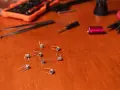 Varias resistencias comerciales de vapeo esparcidas sobre una mesa de madera, junto a herramientas como pinzas y un destornillador.