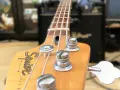 Nahaufnahme des Bass-Kopfes mit Saiten und Stimmmechaniken. Der Schriftzug "Squier by Fender Jazz Bass" ist sichtbar. Perfekt, um den Bass einzustellen.