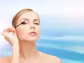Une femme applique du mascara sur ses cils. Apprendre comment mettre du mascara pour un regard intense.