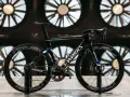 A black S-Works aero bike, designed for speed, is showcased in front of large industrial fans. This is what an aero bike looks like.