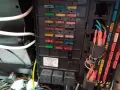 Panel bezpieczników w Mercedesie GL. Widoczne bezpieczniki i przekaźniki, a także etykieta z opisem.