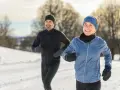Ein Paar genießt das Laufen im Winter. Sie tragen passende Winterkleidung, um sich warm zu halten.