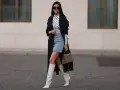Outfit per uscire con un ragazzo: gonna di jeans, top a collo alto con stampa luna, trench nero, stivali bianchi alti e borsa grigia.