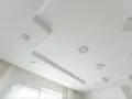 Nowoczesny sufit podwieszany z wbudowanymi kwadratowymi lampami. Widać wyraźnie rozstaw profili, tworzących ciekawe poziomy i kształty.