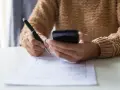 Kobieta z telefonem w dłoni wypełnia formularz, dokonując zgłoszenia darowizny online.
