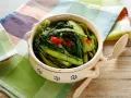 Cicoria in padella, un contorno saporito con peperoncino, servita in una ciotola decorata su un tagliere di legno.