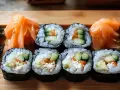 Gotowy sushi przepis na talerzu: rolki z ryżem, ogórkiem i łososiem, podane z marynowanym imbirem i zielonymi dodatkami.