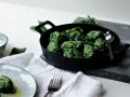 Malfatti, was ist das? Grüne, unregelmäßige Klößchen aus Spinat und Ricotta in einer Pfanne, daneben ein Teller mit mehr Malfatti und Parmesan.