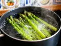 Asperges vertes bouillonnant dans une casserole, prêtes pour une recette simple et savoureuse.