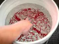 En hand rör vid vatten med röda mönster i en hink. En **grit guard** fångar upp smuts och skyddar din bils lack.