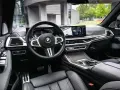 Wnętrze BMW x7: skórzana tapicerka, nowoczesny kokpit z dwoma ekranami i sportowa kierownica.