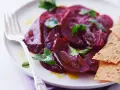 Ein Teller mit traditionellem Rote Bete Salat, garniert mit Petersilie und serviert mit knusprigen Crackern.