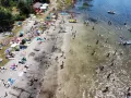 Tłoczna plaża nad jeziorem, ludzie opalają się, kąpią i pływają. Wakacyjny wypoczynek na **jeziorach lubelskich**.