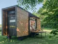 Casa móvil de madera en un terreno no urbanizable, con mesa desplegable y sillas.