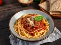 Pyszne spaghetti bolognese, przygotowane według oryginalnego przepisu, z bogatym sosem mięsnym i listkiem bazylii.
