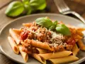 Penne z sosem bolognese, posypane parmezanem i udekorowane bazylią. Pyszne potrawy włoskie na talerzu.