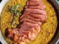 Arroz amarillo con chuletón a la parrilla y romero en paellera.