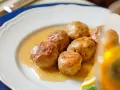 Polpette al limone succulente in un piatto bianco, con una fetta di limone e basilico.