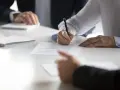 Kobieta podpisuje dokument, co może oznaczać wyłączenie z masy upadłości. Obok leży notatnik.