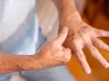Osoba masuje dłoń, próbując złagodzić ból prawej ręki.