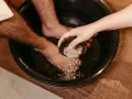 A hand pours pink salt into a foot bath, adding to the foot detox ingredients for a relaxing soak.