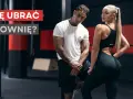 Jaki strój na siłownię? Para w sportowych ubraniach pozuje na tle siłowni.
