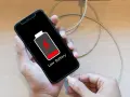 En person kopplar in sin mobil för att ladda mobilen på natten. Batteriikonen visar låg nivå.