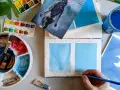 Paleta de acuarelas, pinceles y muestras de pintura azul. Un artista experimenta con técnicas de pintar acuarela.