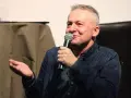 Bogusław Linda opowiada o swoich rolach w serialach i programach, trzymając mikrofon.