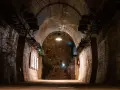 Wnętrze tunelu w Górach Sowich. Betonowe ściany, łukowe sklepienie i oświetlenie tworzą mroczny klimat.