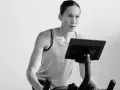 Focused woman powering through a hiit cycle workout on a stationary bike, her muscles engaged.