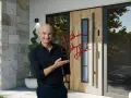 Uśmiechnięty mężczyzna prezentuje nowoczesne drzwi zewnętrzne KMT. Zobacz nasz kmt drzwi zewnętrzne katalog i wybierz idealne wejście do domu.