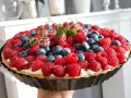 Prosta tarta z budyniem, obficie udekorowana malinami i borówkami, wygląda apetycznie.