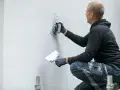 Un ouvrier applique un enduit sur un mur extérieur avec une truelle.