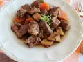 Pyszne wołowina po burgundzku z pieczarkami i marchewką, podana na talerzu.