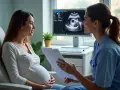 Ciężarna kobieta rozmawia z lekarką przy monitorze z badaniem USG płodu.