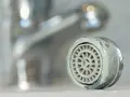 Zwapniony aerator kranu, który pokazuje, jak wyjąć sitko z kranu.