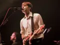 Ben Gibbard chante et joue de la guitare sur scène, éclairé par les projecteurs.