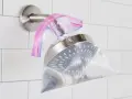 A shower head is submerged in a plastic bag filled with vinegar, secured with a rubber band. This shows how to clean shower head vinegar for a sparkling finish.