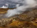 Gunnuhver hot springs: para buchująca z ziemi, zniszczona drewniana konstrukcja, chmury burzowe nad krajobrazem.