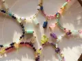 Kolorowe naszyjniki z kamieni szlachetnych, w tym lapis lazuli znak zodiaku, ułożone na talerzu.