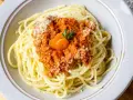 Spaghetti Bolognese, zubereitet im Thermomix, mit Karottenscheiben und Petersilie garniert.