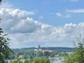 Blick auf die Ratzeburg Altstadt mit Domkirche, umgeben von grünen Bäumen und dem See unter einem dramatischen Wolkenhimmel.