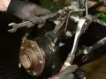 Mechanik dokręca śruby przy piaście, wymieniając łożysko w samochodzie.