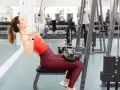 Kvinna tränar rakarmade latsdrag på gym.