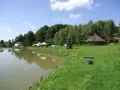 Malownicze dzikie łowiska Małopolska: spokojna woda, zielone wzgórza, drewniana altana i miejsca do wypoczynku.