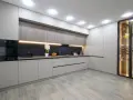 Cocina moderna con armarios grises y vitrina iluminada. El suelo de madera clara es perfecto para suelos para cocinas sin obras, aportando calidez y estilo.