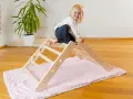 Ein fröhliches Kleinkind erkundet ein Pikler Dreieck. Ab wann Kinder damit spielen können, hängt von ihrer Entwicklung ab.