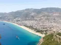Widok na wybrzeże Turcji z miastem, plażą i statkami na turkusowym morzu.